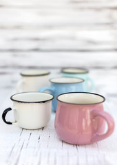 Enameled mugs in retro style on an old wooden background.