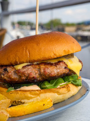 delicious beef burgers with salad trimmings, french fries. Close-up of home made tasty burger with french fries on wooden table.