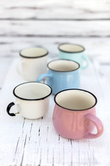 Enameled mugs in retro style on an old wooden background.