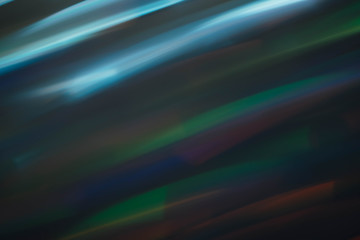 Defocused colored rays. Blur blue and green smeared strokes. Dark abstract background.