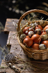 Basket of eggs on old wooden background. Brown farm eggs and quail eggs.