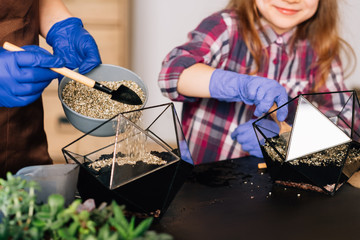 DIY florarium. Earth Day. Cropped shot of mother and daughter pouring wood shavings over soil in...