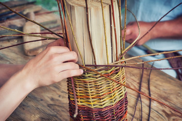 Men hands weave craft basket of tree branches. Vintage work of artisans basket-makers in the old...