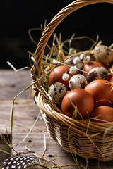 Basket of eggs on old wooden background. Brown farm eggs and quail eggs.
