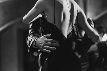 Foto op Canvas Een man en een vrouw dansen tango. Zwart-wit afbeelding © filirovska