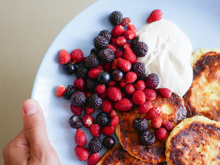 pancakes with berries. and sour cream. Cheesecakes served with lots of fresh berries. Gourmet breakfast - curd cheesecakes, curd pancakes with raspberries, strawberries, blueberries. Close. healthy fo