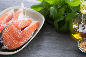 fresh salmon with herbs on white dish on ceramic background