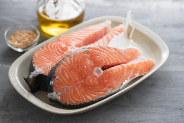 fresh salmon with herbs on white dish on ceramic background