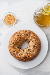 fresh bagel with seeds on white plate on ceramic background