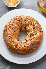 fresh bagel with seeds on white plate on ceramic background