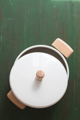 Green open cooking pan on green wooden background