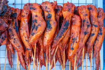 Thai street vendor sells grilled chicken meat at street food market in island Koh Phangan, Thailand. Closeup