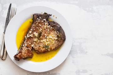 fried tuna with garlic, bay leaf and olive oil on white plate