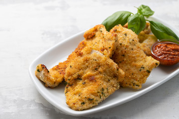 fried chicken breast with sauce on white dish on ceramic background