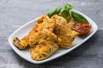 fried chicken breast with sauce on white dish on ceramic background
