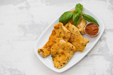 fried chicken breast with sauce on white dish on ceramic background