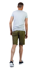 Back view of going handsome man in shorts.