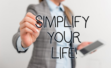 Text sign showing Simplify Your Life. Business photo text focused on important and let someone else worry about less ones Business woman pointing in empty space with pen and mobile phone