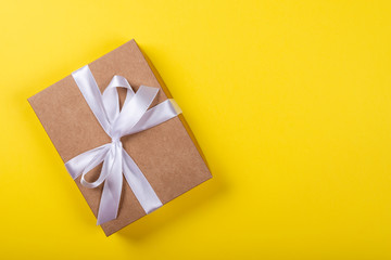Gift box with bow on yellow background. Space for text on the right side of the image.