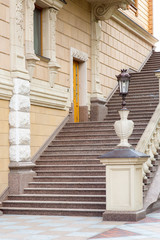 architectural stone staircase near the facade of the building with railings and balustrades with a pedestal for a stone vase with an iron street lamp in retro style.