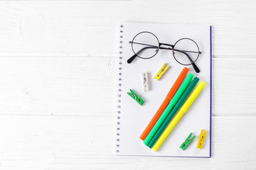 Green and yellow markers, notebook and glasses. The concept of school, creativity, childhood