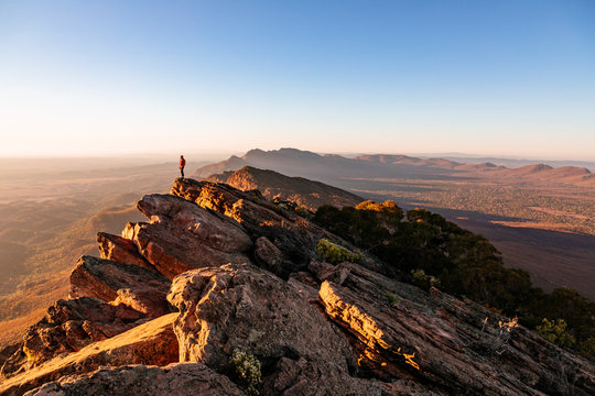 Woman standing on cliff at St Mary Peak during sunrise