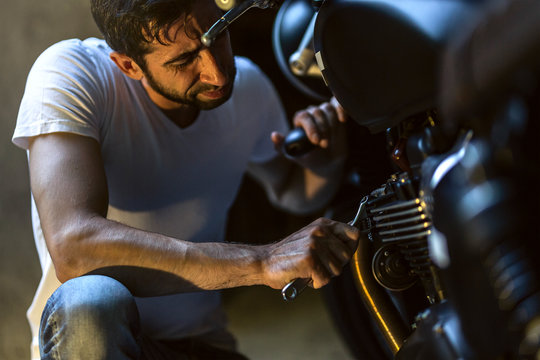  Man Repairing His Motorcycle In The Garage.