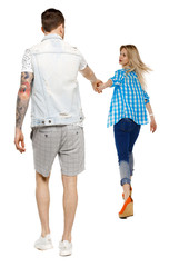 Back view of going couple. walking friendly girl and guy holding hands.