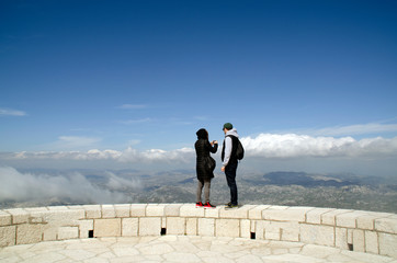 A guy and a girl are photographing a beautiful mountain landscape from the height of a stone tower.