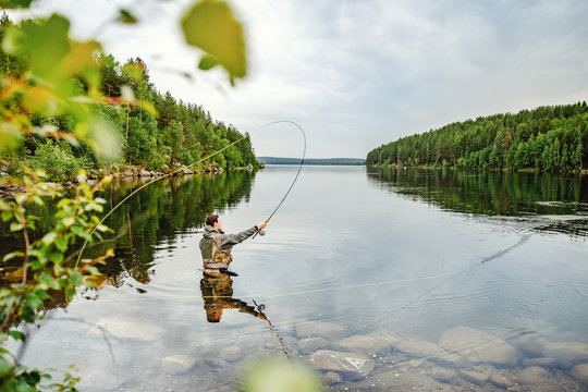 Fisherman using rod fly fishing in mountain river