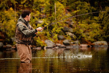 Fisherman using rod fly fishing in mountain river