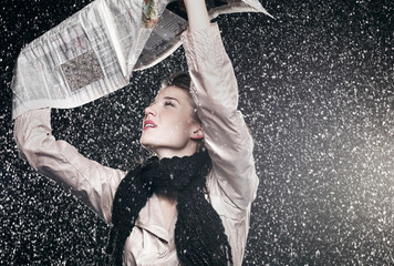 Woman sheltering from rain under newspaper.