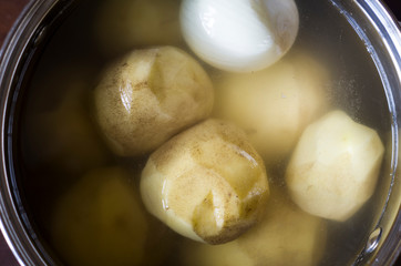 Raw fresh peeled potatoes and onion in the pan with water