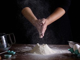 Chef hand clap and white flour on black background