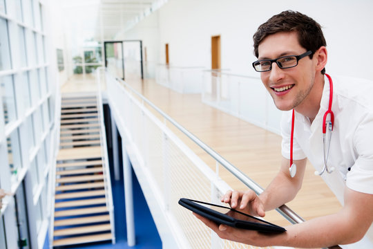 Germany, Bavaria, Diessen am Ammersee, Young doctor using digital tablet, smiling, portrait