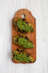 Grilled chimichurri chicken breast on a rustic wooden board on a white wooden background, top view. Close-up.