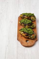 Grilled chimichurri chicken breast on a rustic wooden board on a white wooden background, low angle view. Space for text.