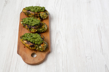 Grilled chimichurri chicken breast on a rustic wooden board on a white wooden background, low angle view. Copy space.