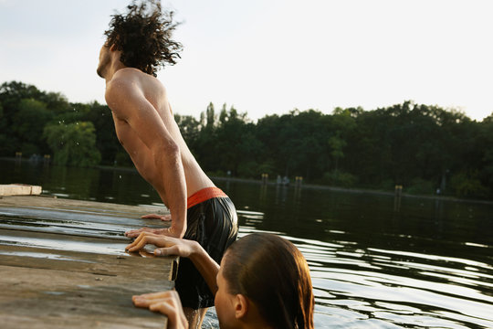 Germany, Berlin, Young couple in River Spree, young man climbing on jetty