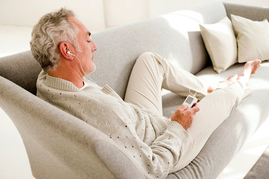 Mature man listening to MP player, elevated view
