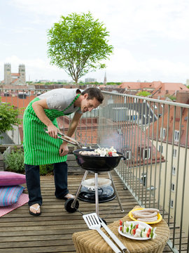 Man preparing barbecue on balcony