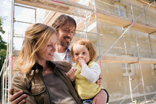 Young family in front of New Home Under Construction