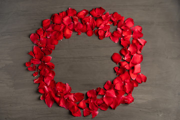 Obraz premium A round frame made of rose petals on a dark cement table.