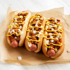 Homemade Detroit style chili dog on a white wooden table, low angle view. Close-up.