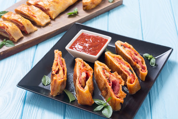 Pizza roll stromboli with cheese salami olives and tomatoes
