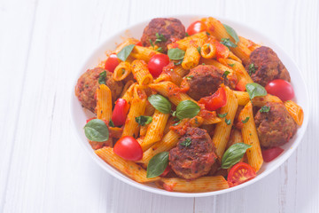 Italian penne pasta with meatballs and tomatoes