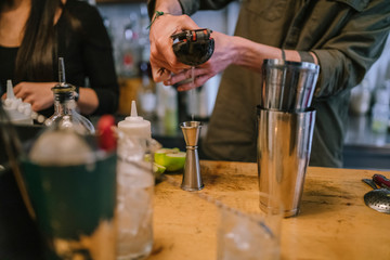 Young barman prepares an alcoholic cocktail in the bar