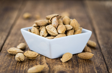 Old wooden table with roasted Almonds (in the shell)
