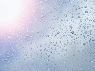 Raindrops on glass blue sky background.