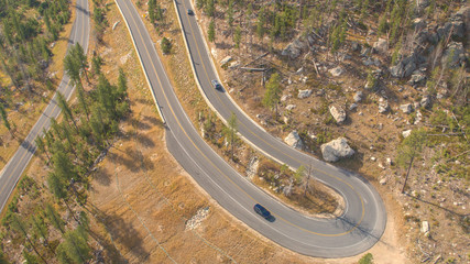 AERIAL Cars driving along the snaking road up the forested mountain pass highway